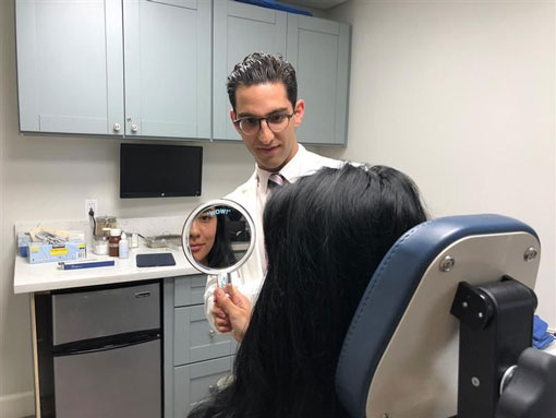 Dr. Samimi holding up a mirror for patient
