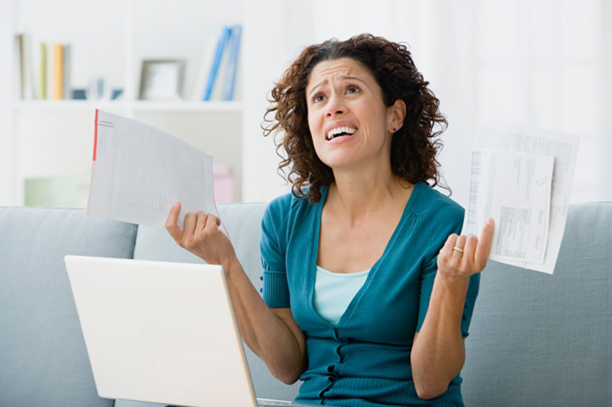 Woman holding papers in front of a laptop